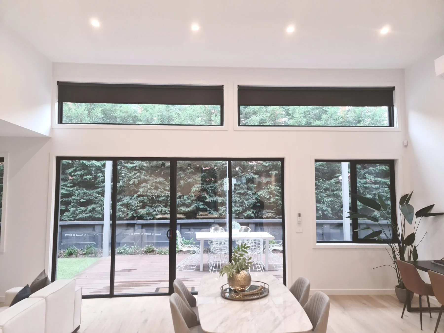 Living and dining room with black roller blinds on the highlight windows