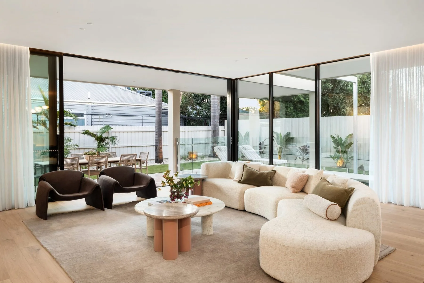 Living room with sheer curtains framing the garden and pool